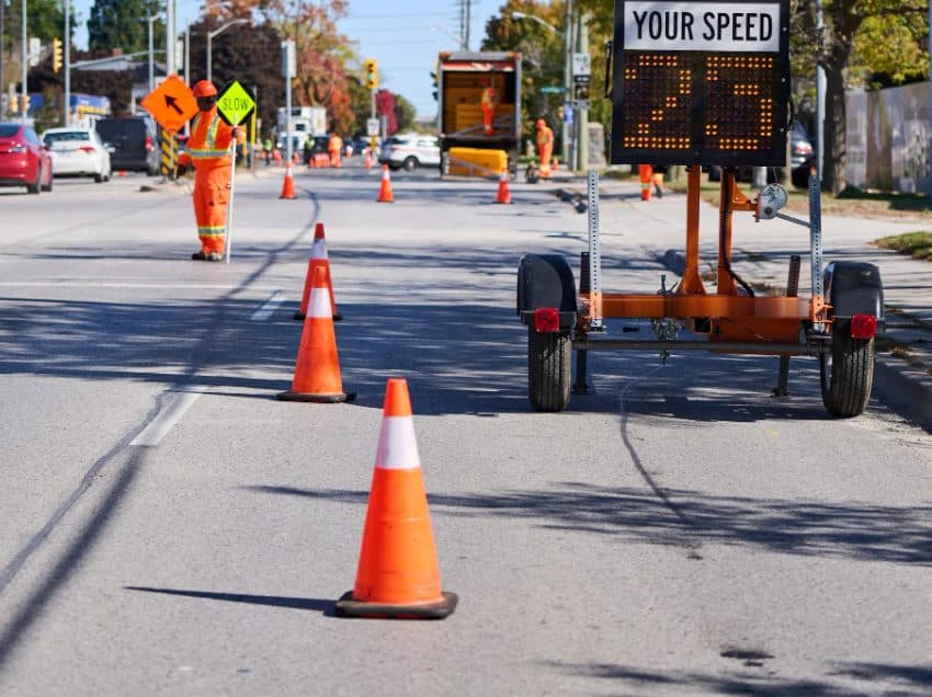 Traffic control person, cones and a speed trailer on a lane closure